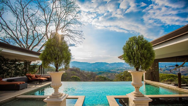 A pool with a mountain view, two large vases, and outdoor seating. - La Toscana Hills (Atenas)
