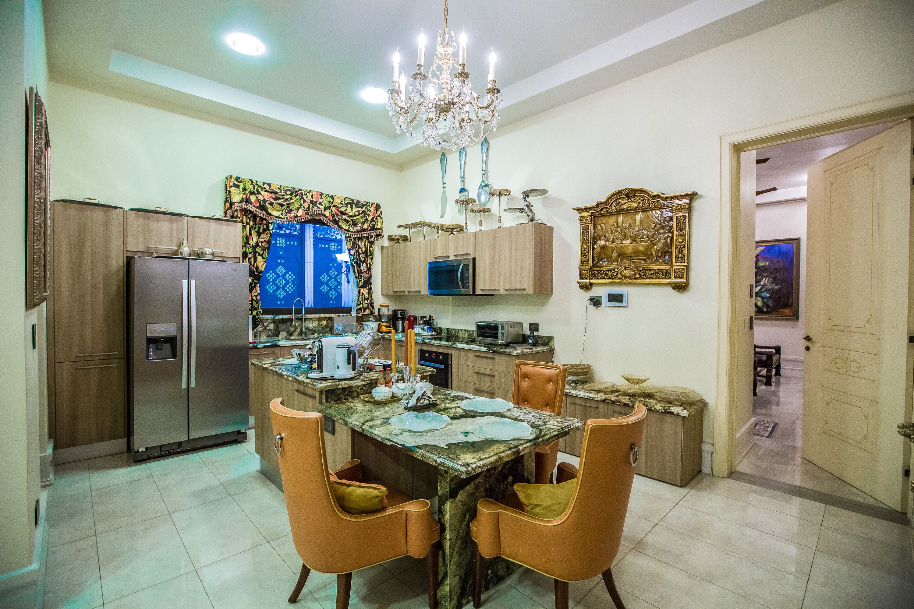 A modern kitchen with a central island, built-in appliances, and a chandelier.