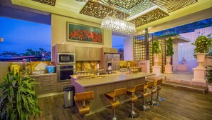 A modern kitchen with a central island, bar stools, and a large window overlooking a cityscape. - La Toscana Hills (Atenas)