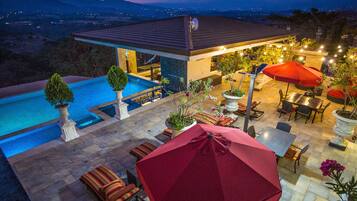 A rooftop pool area with a dining setup and a view of the landscape.