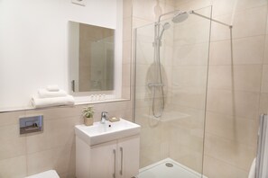 Executive appartement | Badkamer | Een douche, een haardroger, pantoffels, handdoeken