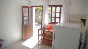 A kitchen with a refrigerator, wooden table, and two windows with curtains.