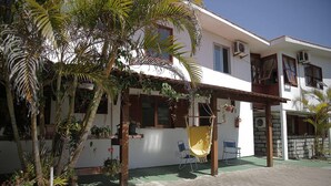 A two-story house with a balcony, potted plants, and a yellow hammock.