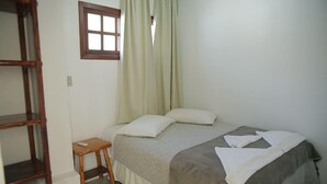 A bedroom with a bed, a small table, a window, and a wooden ladder.