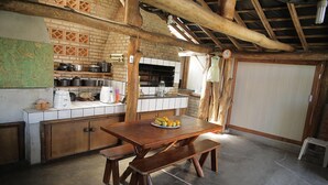 A rustic kitchen with a wooden table, bench, and brick wall.