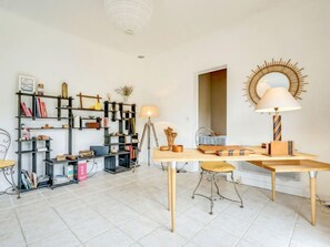A modern living room with a wooden coffee table, a floor lamp, a bookshelf, and a sunburst wall decoration.