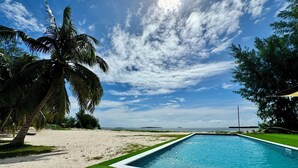 Une piscine avec vue sur l’océan et les palmiers.