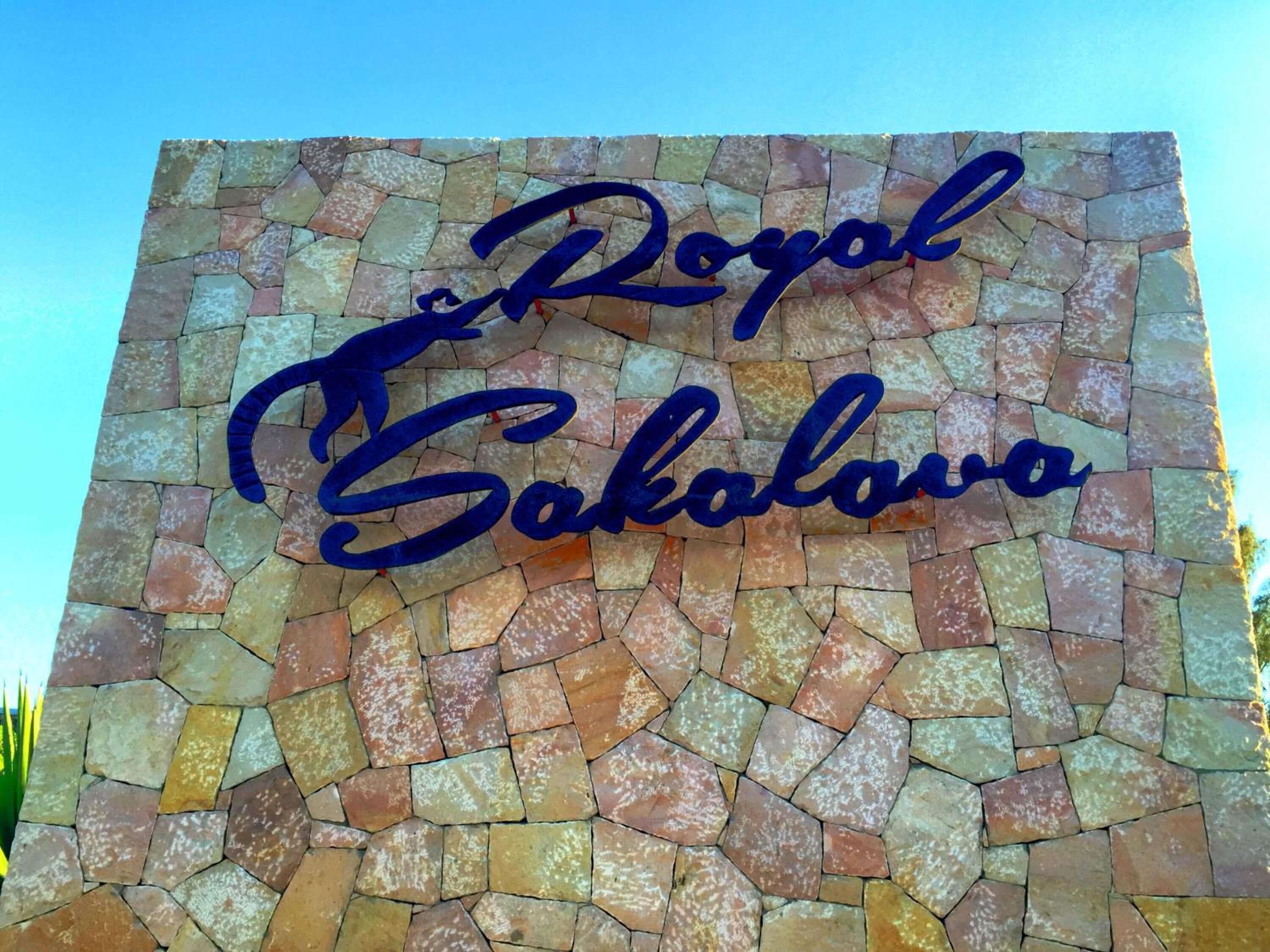 Un muro de piedra con el texto "The Royal Sokolovo" en letras cursivas azules.