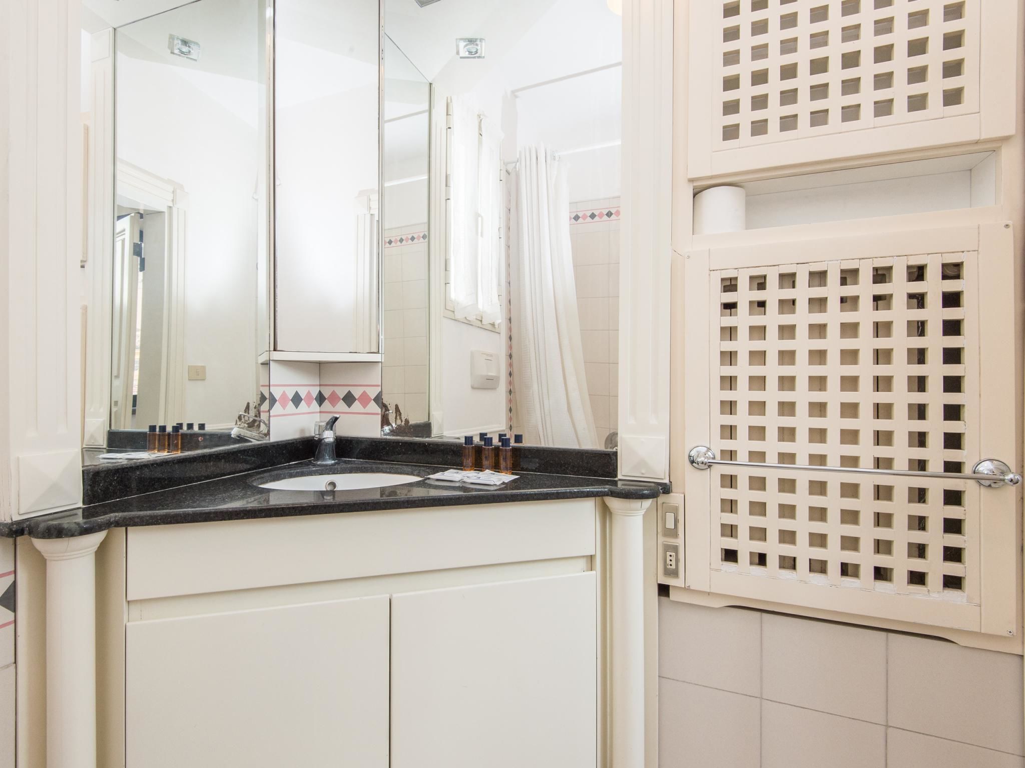 Een badkamer met een witte wastafel, spiegel en douchegordijn.