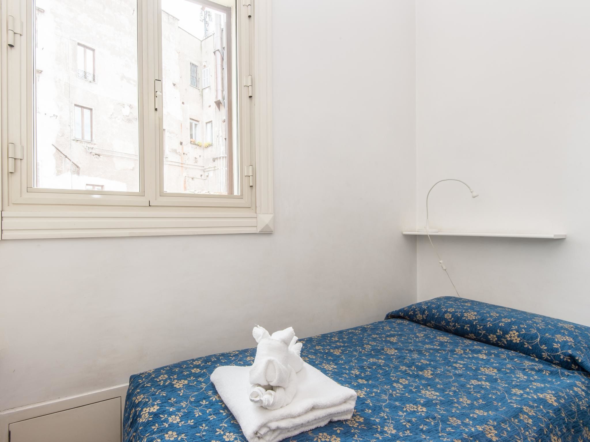 Una stanza con un letto, una finestra e una parete bianca.