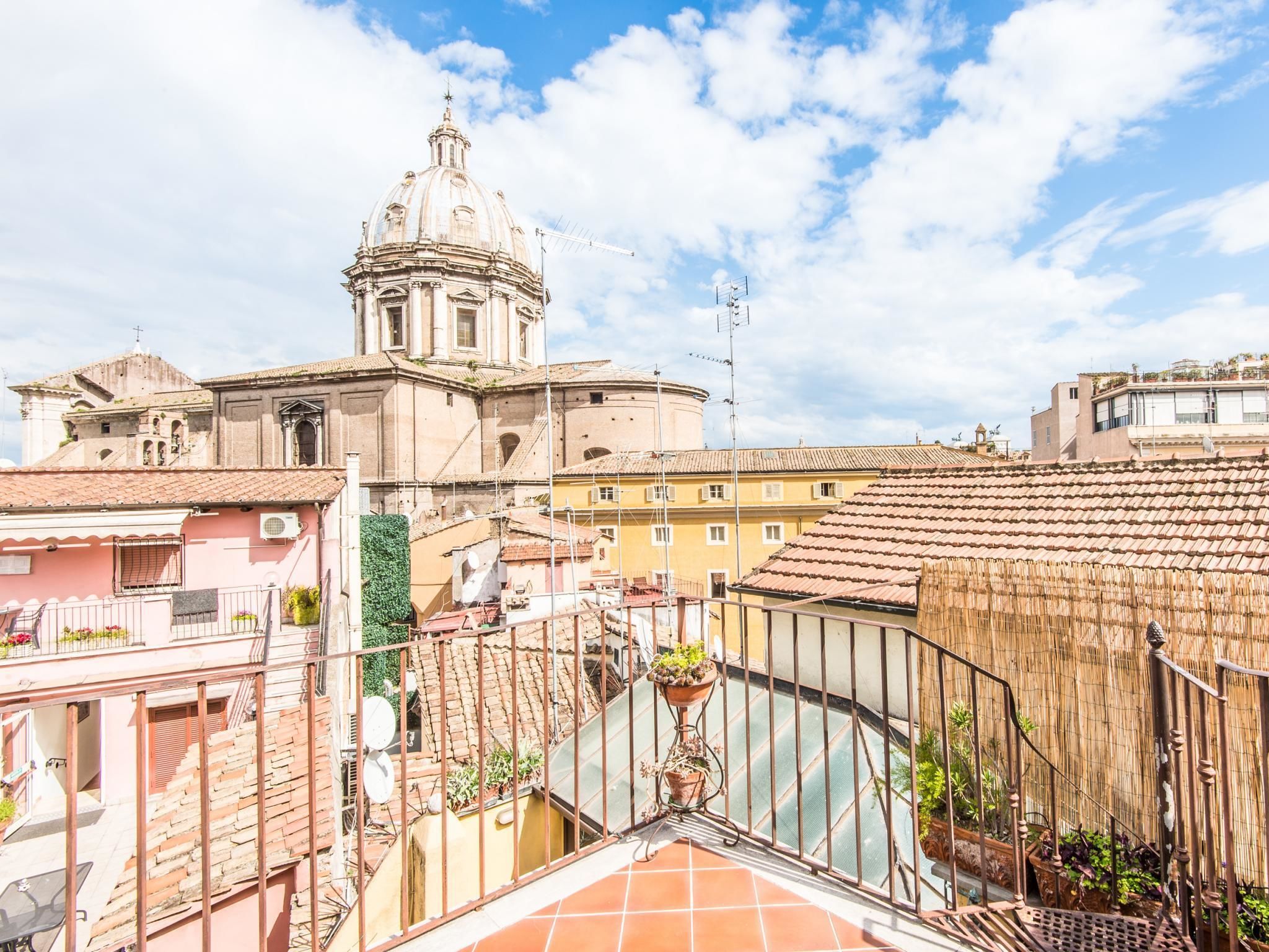 Vista de un edificio histórico con una cúpula, rodeado de edificios con techos de teja rojiza.