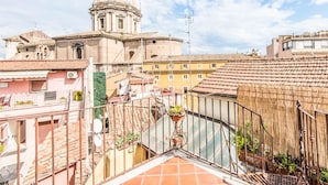 A view of a historic building with a dome, surrounded by terracotta-roofed buildings.