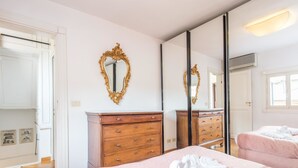 A hotel room with a wooden dresser, a large mirror, and a bed with white towels.