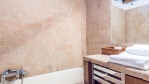 A bathroom with a bathtub, a wooden vanity, a mirror, and a brick wall. - RSH Elegant Apartment Campo dei Fiori (Rome)