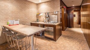 A compact kitchen with a brick wall, a bar counter with stools, a stove, and a sink. - RSH Elegant Apartment Campo dei Fiori (Rome)