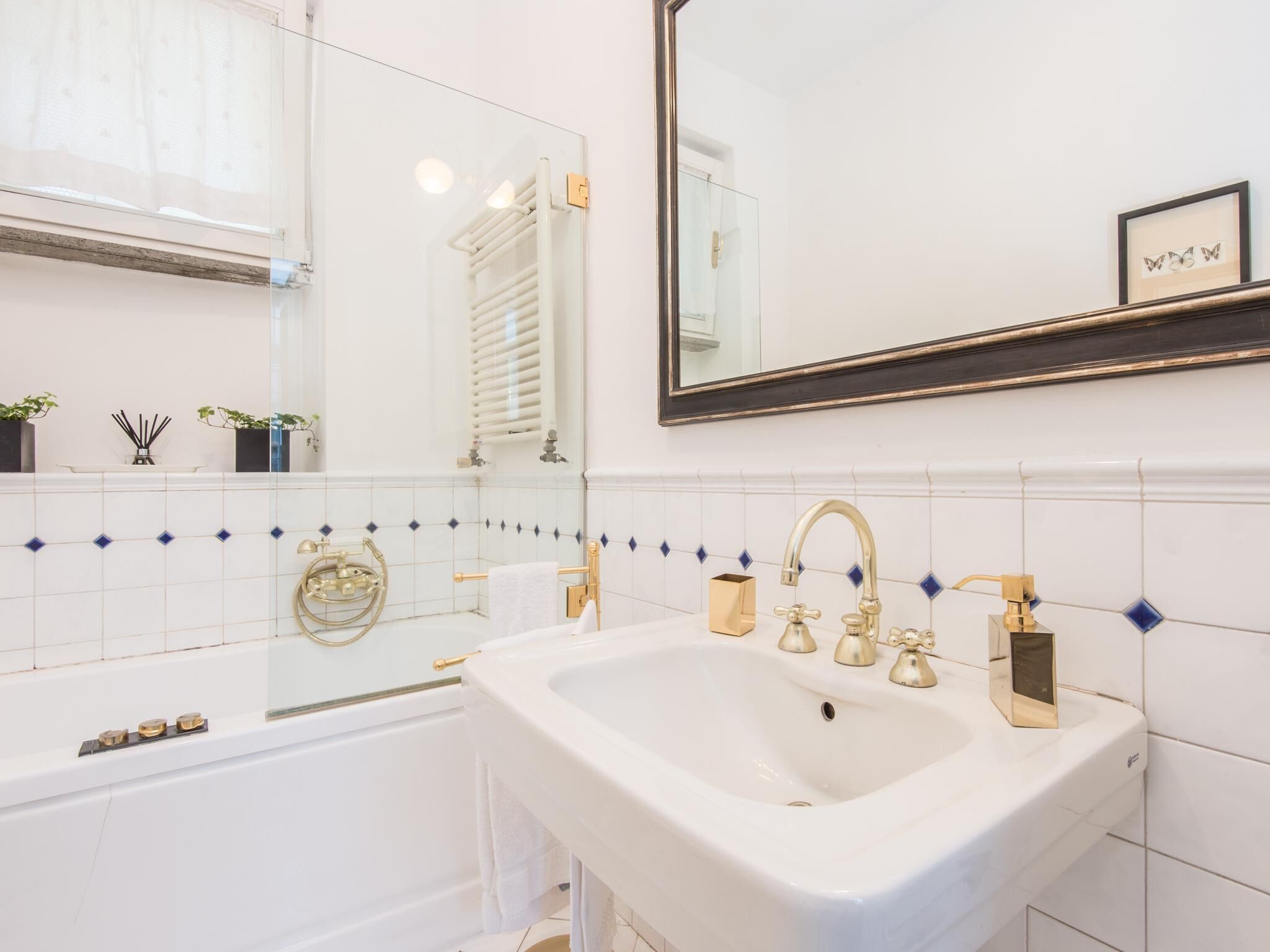 Une salle de bain avec un lavabo blanc, des robinets dorés et une baignoire.