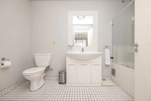 A bathroom with a toilet, sink, and shower area.