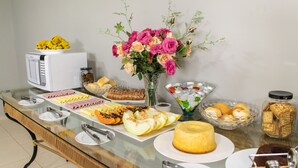 Une table de buffet avec divers plats, un four à micro-ondes et un vase de fleurs.
