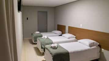 A hotel room with two single beds, a wooden headboard, and a television mounted on the wall.