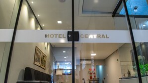 L’entrée d  ’un hôtel, avec un comptoir d’accueil, un espace salon et une enseigne indiquant « HÔTEL CENTRAL ».