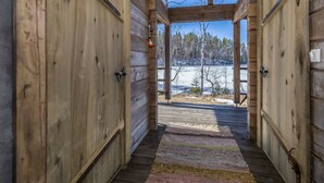 A log cabin interior with a wooden floor, a rug, and a view of a snowy landscape through a large window. - Riemukaari by Interhome (Pertunmaa)
