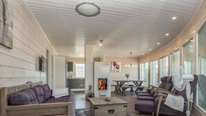 A cozy cabin interior with a wooden ceiling, a fireplace, a dining area, and a seating area with a fan. - Riemukaari by Interhome (Pertunmaa)