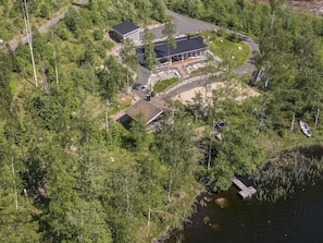 Vue aérienne d’une propriété comprenant un bâtiment principal, un quai et un petit bateau.