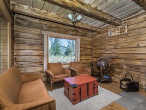 A cozy cabin interior with wooden walls, a large window, a ceiling fan, and a red chest of drawers. - Riemukaari by Interhome (Pertunmaa)