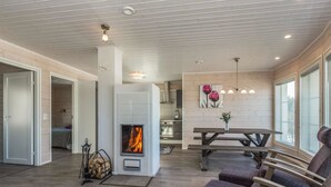 A cozy living room with a fireplace, wooden furniture, and a dining area with a bench and table. - Riemukaari by Interhome (Pertunmaa)