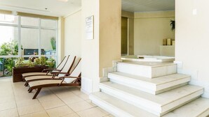 Un intérieur moderne avec un escalier, un coin salon avec des fauteuils et une vue sur l’extérieur.