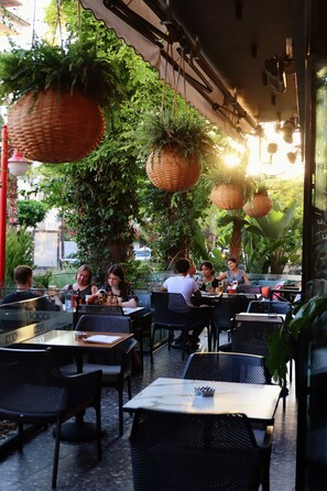 An outdoor cafe with tables and chairs, surrounded by greenery and hanging baskets. - Comfort Suites (Alanya)