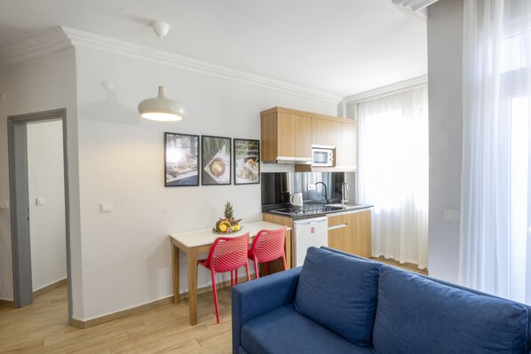 Un apartamento moderno con kitchenette, un comedor con sillas rojas y un sofá azul.