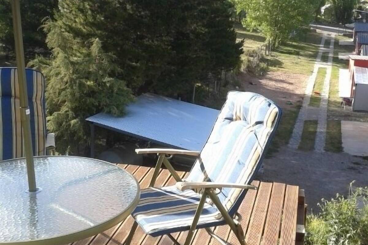 Un patio al aire libre con una mesa, sillas y un paraguas azul.