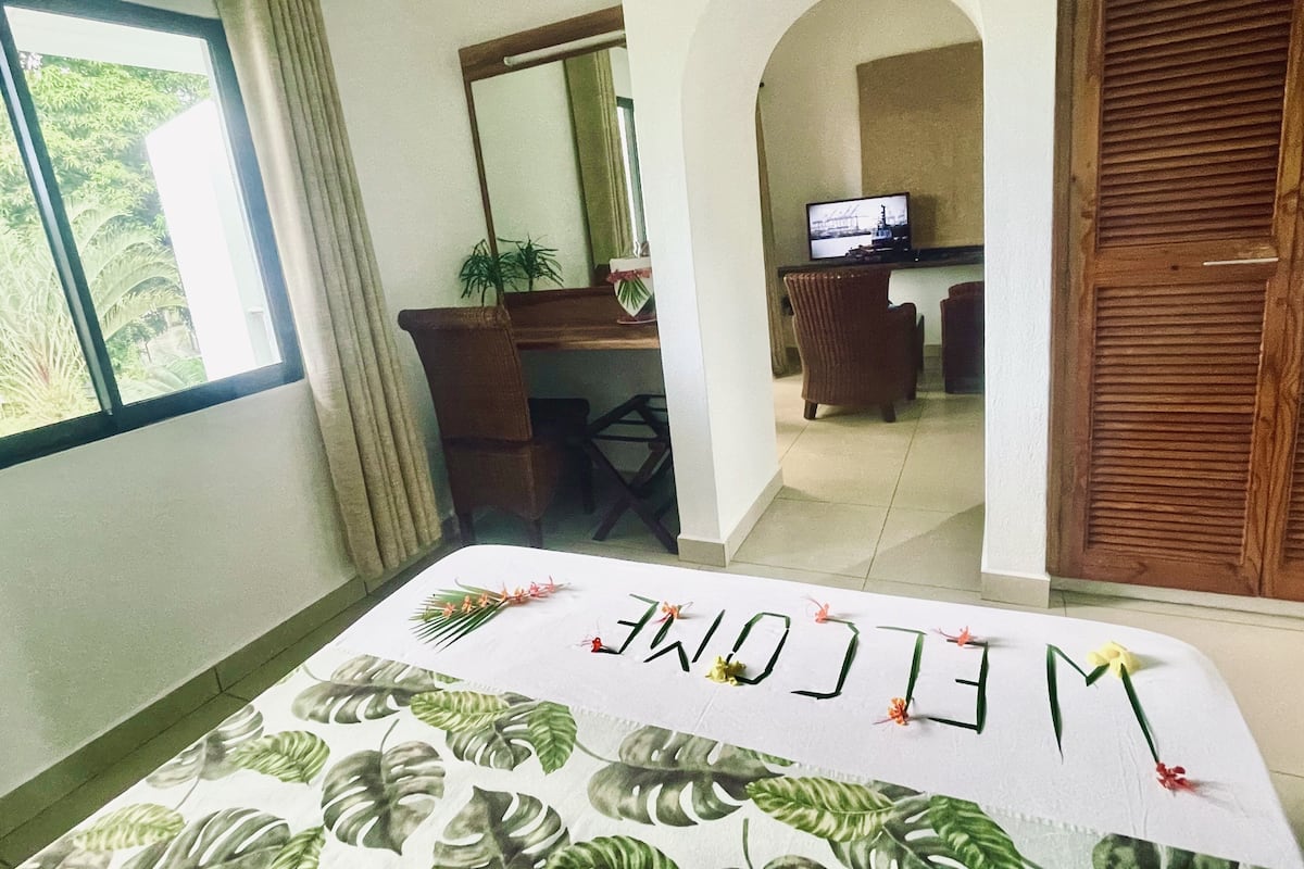 A hotel room with a bed, a desk, a television, and a view of the outdoors.