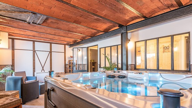 Zona de spa con un jacuzzi, techo de madera y asientos.