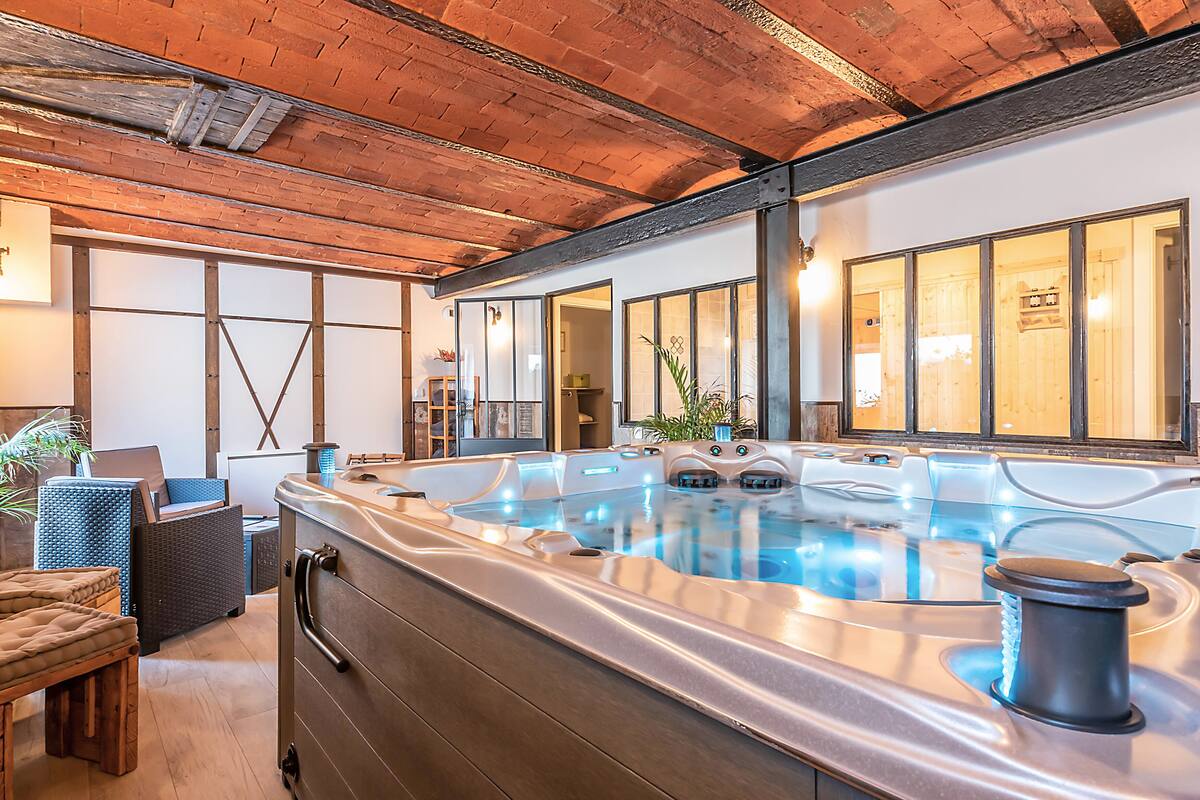 A spa area with a hot tub, wooden ceiling, and seating.