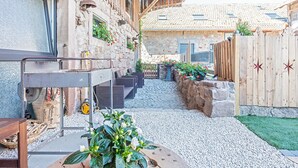 Un patio con muro de piedra, cerca de madera y camino de grava.