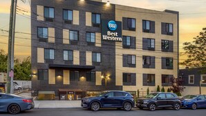 Een meerlaags hotel met een moderne gevel van baksteen, een opvallend ‘Best Western’ bord en een parkeerplaats met meerdere auto's.