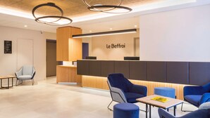A modern reception area with a wooden reception desk, blue seating, and a ceiling with circular light fixtures. - Best Western Le Beffroi (Loos)