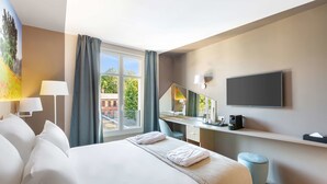 A hotel room with a large bed, a desk, a chair, a TV, and a window with curtains. - Best Western Le Beffroi (Loos)
