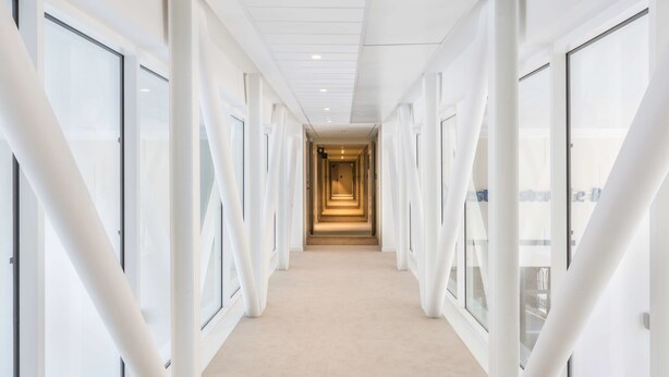 A modern, well-lit hallway with glass doors on both sides, leading to a central corridor. - Best Western Le Beffroi (Loos)