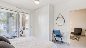 Et moderne soveværelse med en stor seng, et skrivebord med stol og udsigt gennem en skydedør.