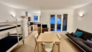En kompakt opholdsstue med køjeseng, spiseplads, køkken og sofa.