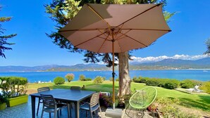 En terrasse med et bord og stole, en grøn stol og en stor parasol.