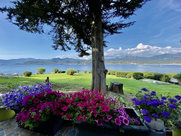 Ein Garten mit Blumenbeeten und Blick auf einen See und Berge.