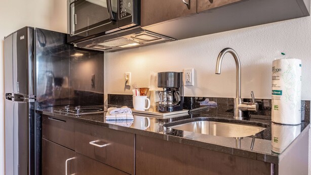 A modern kitchen with stainless steel appliances, a coffee maker, and a sink. - Studio 6 Lake Charles, LA (Lake Charles)