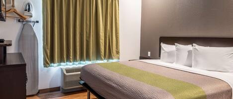 Quarto de hotel com cama, mesa de cabeceira, aquecedor, janela com cortinas e aquecedor fixado na parede.