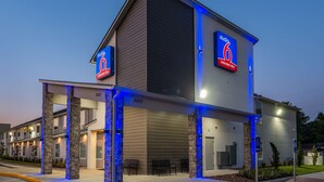 A modern hotel with a 'Studio 6' sign, outdoor seating, and a parking sign. - Studio 6 Lake Charles, LA (Lake Charles)
