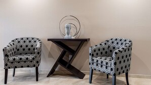Two patterned armchairs and a dark wooden table with a glass sculpture between them. - Studio 6 Lake Charles, LA (Lake Charles)