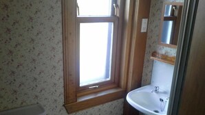 A bathroom with a toilet, a sink, a window, and a mirror. - The Hawthorns (Drymen)